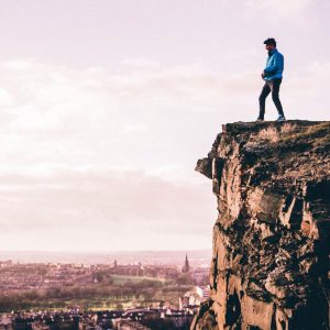 a man stands on a cliff overlooking edinburgh from arthur's seat