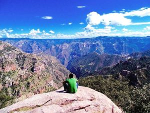 a hiker rests with a magnificent view over the copper canyon mexico