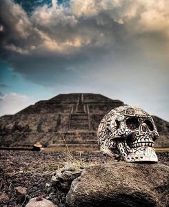 an ornate skull rests at the forefront of an ancient pyramid in teotihuacan mexico